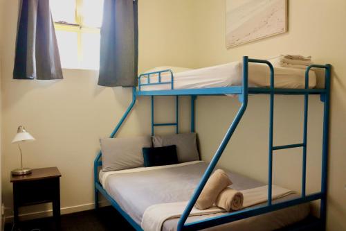 two bunk beds in a room with a lamp at City Backpackers HQ in Brisbane