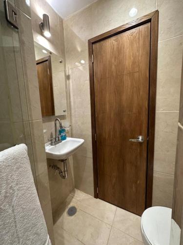 La salle de bains est pourvue d'une porte en bois et d'un lavabo. dans l'établissement Loft privado cerca del Jardín Principal de Sayula, à Sayula