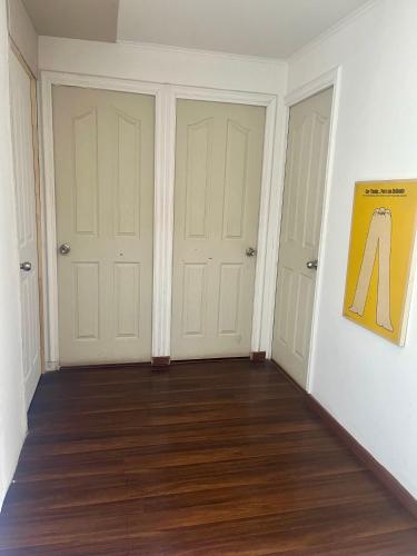 an empty room with two doors and wood floors at Hostel Tu Espacio RE - Habitaciones cerca del Aeropuerto in Santiago