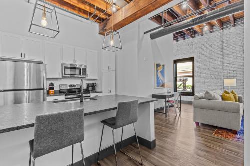 a kitchen and living room with a counter and chairs at Brick & Bed Riverfront Lofts, PC 102 in Saint Louis
