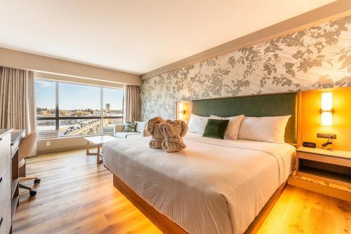 a bedroom with a large bed with a teddy bear on it at Park Town Hotel in Saskatoon