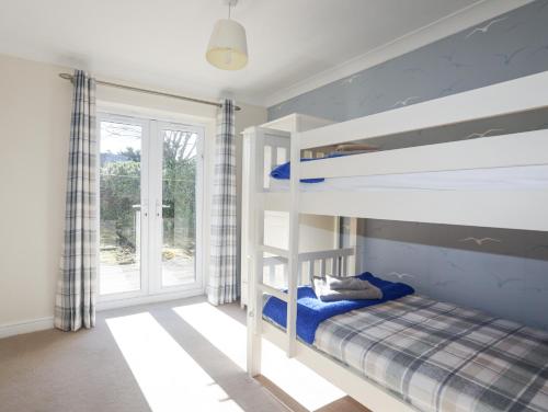 a bedroom with two bunk beds and a window at Tegfan in Holyhead