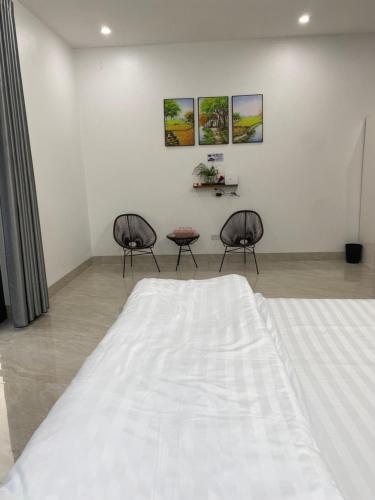 a bedroom with two chairs and a large bed at Tamcoc Motel in Văn Lâm