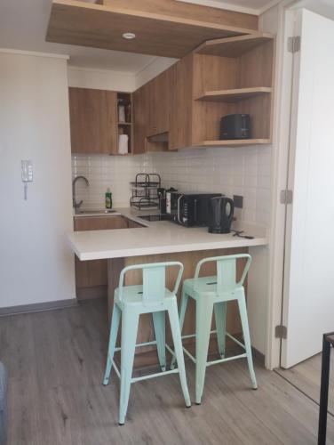 uma cozinha com dois bancos e um balcão em Precioso y confortable Departamento em Santiago