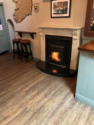 a living room with a fireplace and two stools at Cuckoos Corner in Teach Munna