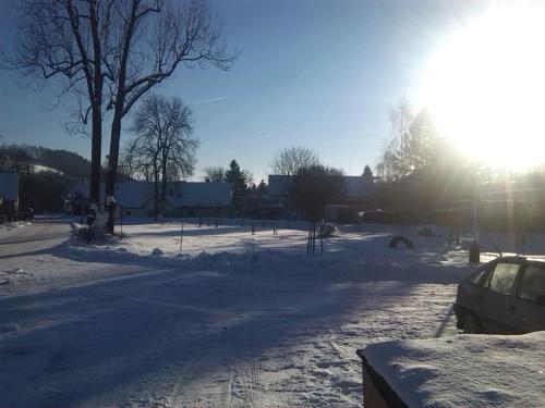 a street covered in snow with the sun shining at Pension Baron in Vrchlabí