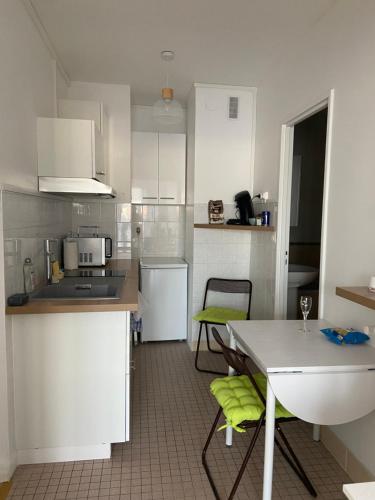 a kitchen with white cabinets and a table with green chairs at Joli studio avec balcon in Vendôme