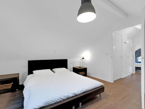 a white bedroom with a large bed and a lamp at Boszicht Reutum in Beekdorp