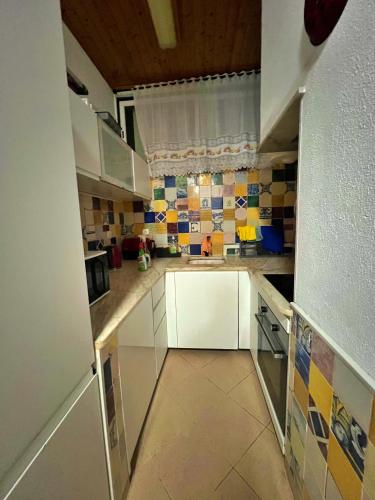 a kitchen with white cabinets and tiles on the wall at Sulemange Rooms Azeitão 25 minutes to Lisbon in Azeitao