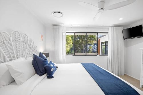une chambre avec un grand lit blanc avec des oreillers bleus dans l'établissement Waves Retreat - Coastal Style Home near Warana Beach, à Parrearra
