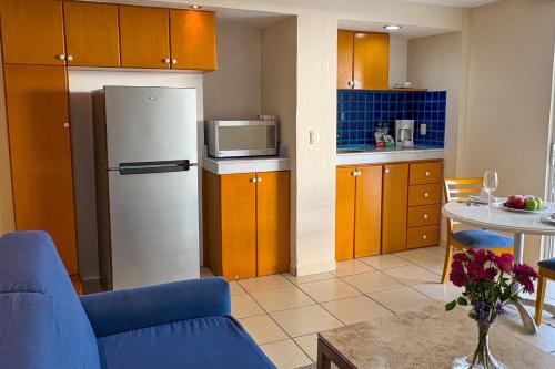 a kitchen with a refrigerator and a table with a blue couch at Ocean view & direct beach access! in Puerto Vallarta
