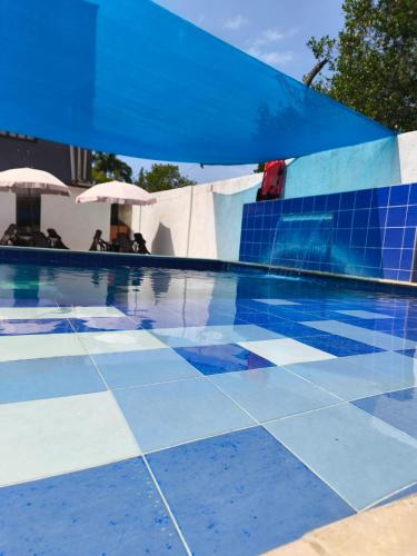 a swimming pool with a blue tile floor and umbrellas at Hotel Palmetto Beach Coveñas in Coveñas