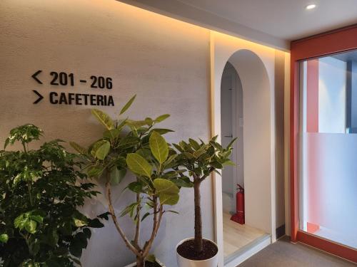 a hallway with plants and a sign on the wall at Hotel No 25 Gimhae cityhall in Gimhae