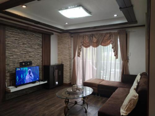 バギオにあるMajestic Staycation Apartmentsのソファとテレビのあるリビングルーム