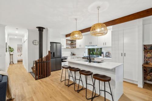 a kitchen with a island and bar stools at Tamborine Creek Stay - Fireplace and close to Theme Parks & Mount Tamborine in Wongawallan