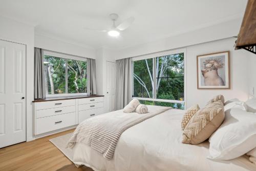 a white bedroom with a large bed and windows at Tamborine Creek Stay - Fireplace and close to Theme Parks & Mount Tamborine in Wongawallan