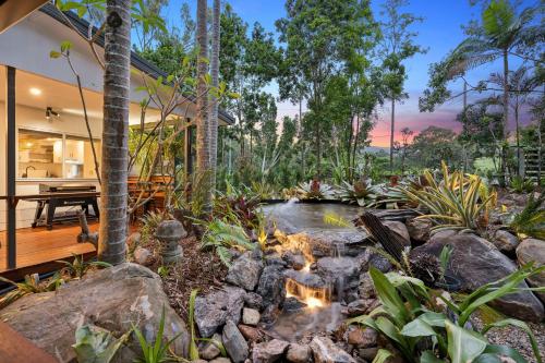 a garden with a pond and a house at Tamborine Creek Stay - Fireplace and close to Theme Parks & Mount Tamborine in Wongawallan