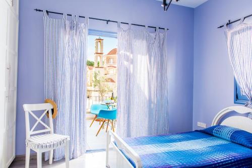 a bedroom with blue walls and a bed and a chair at Eva's House in Stroumbi