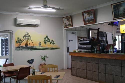 a restaurant with a counter and tables and chairs at Victory Hotel Motel Gympie in Gympie
