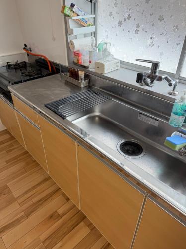 a kitchen with a stainless steel sink and a stove at 自然体験と石窯のある古民家民泊アジールAsyl in Hirosaki