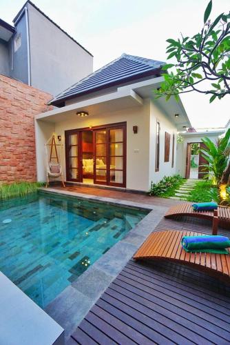 a house with a swimming pool in front of a house at Happy Nest Canggu in Tumbak Bayuh