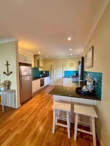 a large kitchen with a counter and chairs in it at Open Plan Coastal Beauty in Patonga Beach in Patonga
