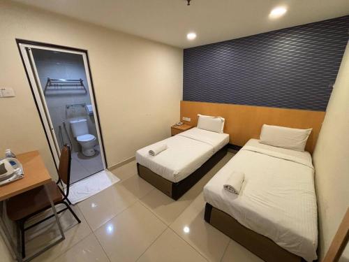 a hotel room with two beds and a desk at Signature Hotel by Easy Nap in Puchong
