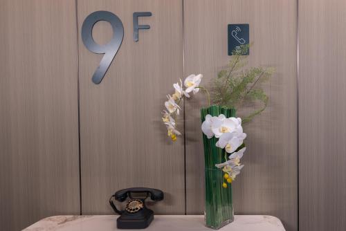 a vase with flowers in it next to a clock at Atour Hotel Canton Tower Pearl River Binjiang Road East Guangzhou - Free Shuttle Bus Service Between Fair And Hotel During The Canton Fair in Guangzhou