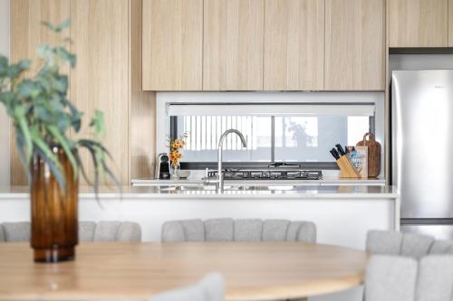 a kitchen with a table and a sink and a refrigerator at Stafford St Apartments by Urban Rest in Adelaide