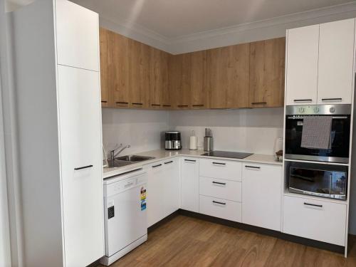 a white kitchen with wooden cabinets and appliances at Shoreline Bliss in South Beach