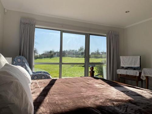 a bedroom with a large bed and a large window at Lotus House in Buckland
