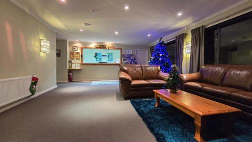 a living room with a couch and a christmas tree at High Peaks Hotel in Fox Glacier