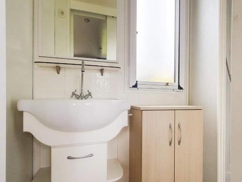 a bathroom with a white sink and a window at Chalet in Friesland near Wadden Sea in Tzummarum