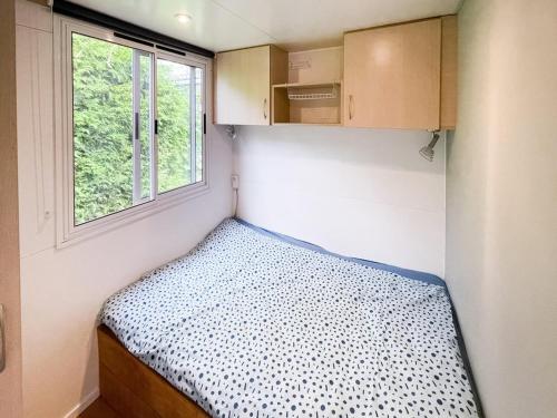 a small bedroom with a bed and a window at Chalet in Friesland near Wadden Sea in Tzummarum