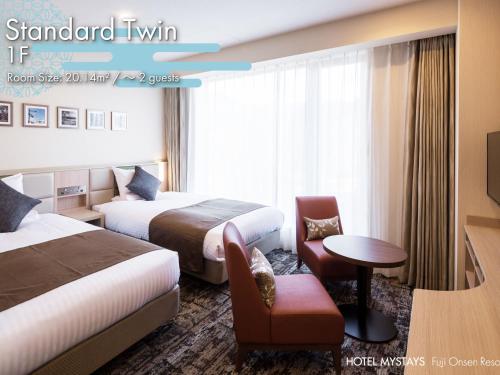a hotel room with two beds and a chair at HOTEL MYSTAYS Fuji Onsen Resort in Fujiyoshida