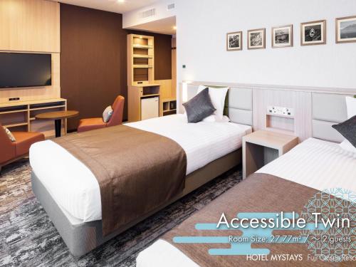 a hotel room with two beds and a tv at HOTEL MYSTAYS Fuji Onsen Resort in Fujiyoshida