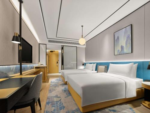 a hotel room with two beds and a desk at Hilton Garden Inn Huangshan Scenic Area South Gate in Huangshan