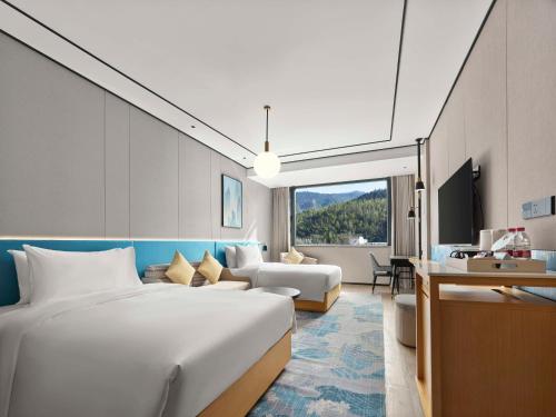 a bedroom with a large bed and a living room at Hilton Garden Inn Huangshan Scenic Area South Gate in Huangshan