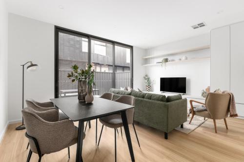 a living room with a couch and a table and chairs at Foundry Lane Apartments by Urban Rest in Bowden