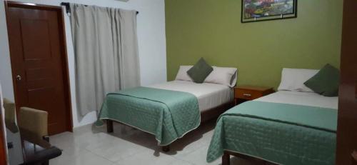 zwei Betten in einem Zimmer mit grünen Wänden in der Unterkunft El Ausente in Ciudad Valles