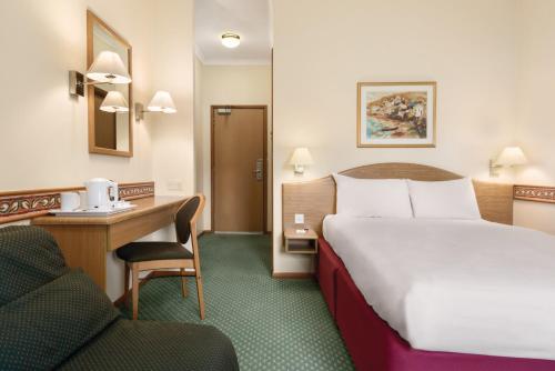 a hotel room with a bed and a desk and a chair at Days Inn by Wyndham Donington in Castle Donington
