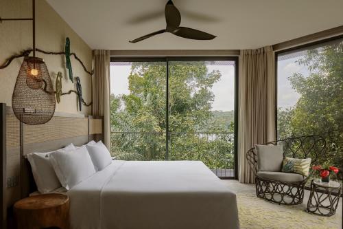 a bedroom with a bed and a large window at Mandai Rainforest Resort by Banyan Tree in Singapore