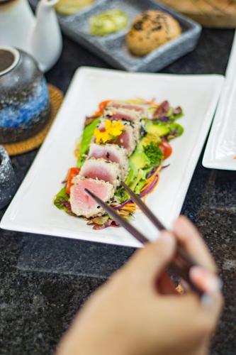 a person eating a plate of food on a table at Kastara Resort in Ubud