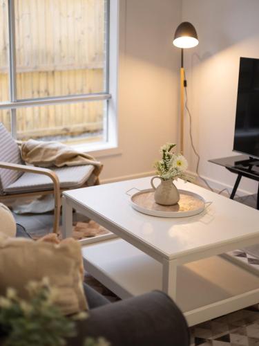 a living room with a table with a vase on it at Cozy Designer 4 Bedrooms Home Near Local Shops in Browns Plains