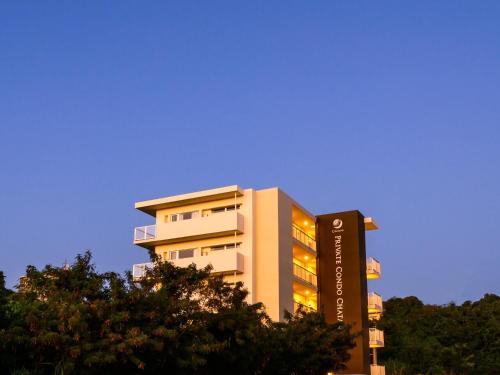 a tall building with a sign in front of trees at Private Condo Chatan Jagaru by Coldio Premium in Chatan