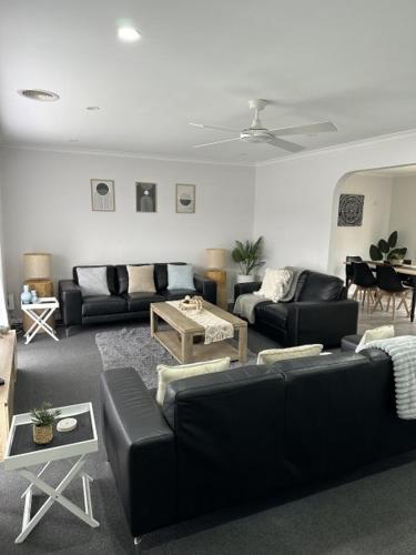 a living room with black couches and a piano at Lbarza Family Friendly 3BR with backyard & single garage near Hospitals & Sporting grounds in Shepparton