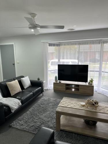 a living room with a couch and a flat screen tv at Lbarza Family Friendly 3BR with backyard & single garage near Hospitals & Sporting grounds in Shepparton