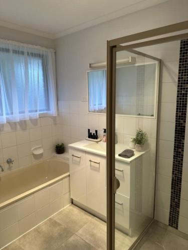 a bathroom with a tub and a sink and a bath tub at Lbarza Family Friendly 3BR with backyard & single garage near Hospitals & Sporting grounds in Shepparton