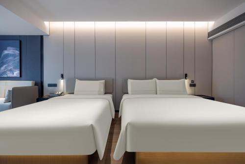 two beds in a room with white walls at Atour Hotel Canton Tower Pearl River Binjiang Road East Guangzhou - Free Shuttle Bus Service Between Fair And Hotel During The Canton Fair in Guangzhou