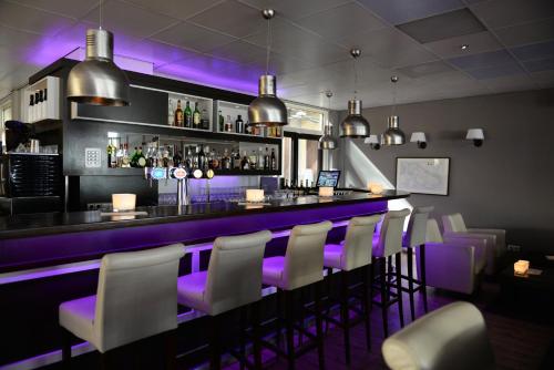 un bar con iluminación púrpura en un restaurante en Fletcher Hotel - Restaurant de Cooghen en De Koog